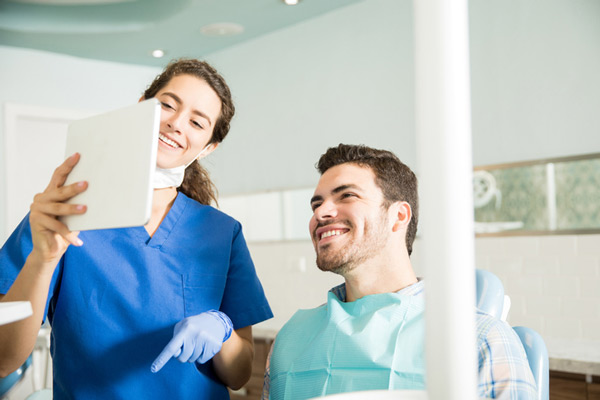 Male patient in dental chair reviewing dental services with dentist, at Fusion Dental Specialists in Happy Valley, OR.